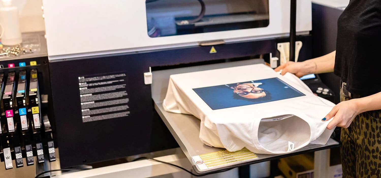 A white t-shirt on the platen of a direct-to-garment printer, full color image printed on the front